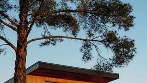 En moderne bygning med en træfacade, store skydedøre og et ørkenlandskab med sten og sparsom vegetation.