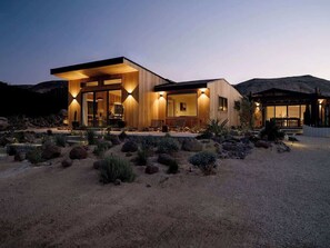 A modern house with a large open patio, surrounded by desert vegetation. - Secluded Retreat | Two Homes, Pool + Firepit (Yucca Valley)
