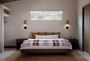 A bedroom with a large bed, two bedside tables, a window, and wall-mounted lamps. - Secluded Retreat | Two Homes, Pool + Firepit (Yucca Valley)