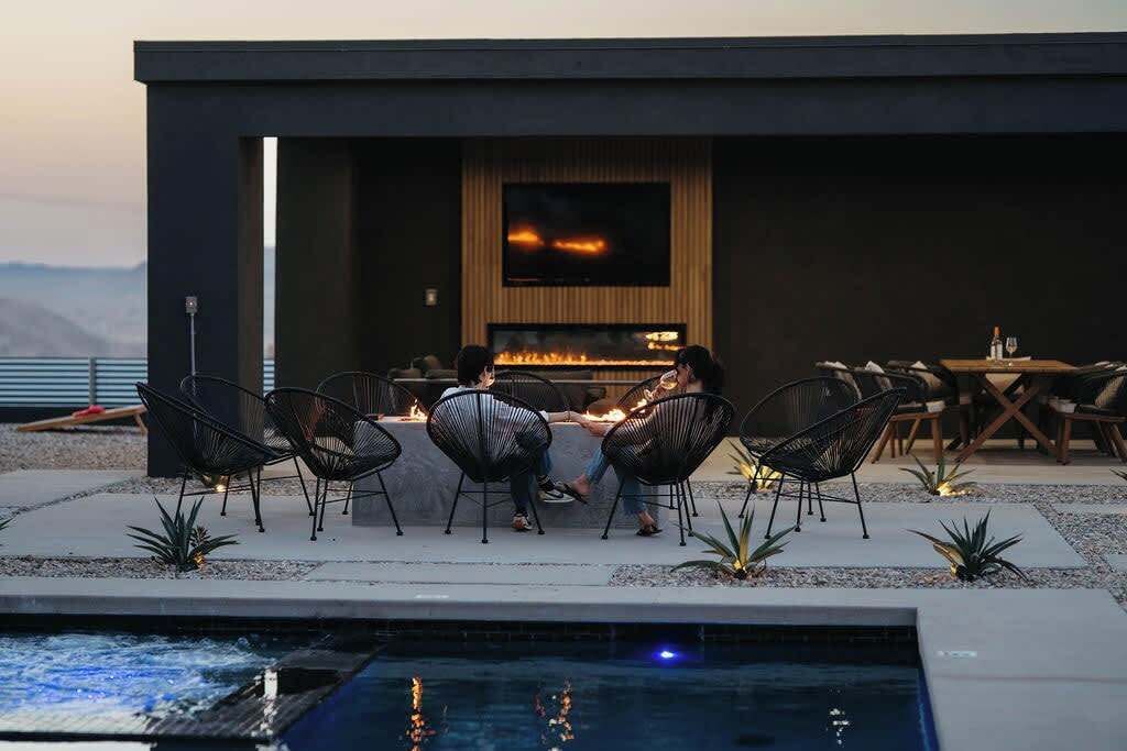 A modern outdoor seating area with a fire feature, pool, and a view of the mountains.