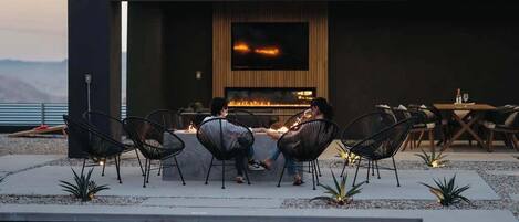 A modern outdoor seating area with a fire feature, pool, and a view of the mountains.