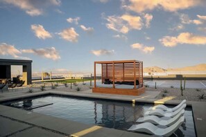 A pool area with a wooden structure, lounge chairs, and a clear sky. - Resort Pool | Pickleball, Sauna + Panoramic Views (Joshua Tree)