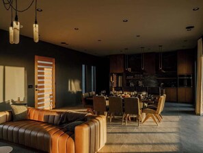 A modern living room with a leather sofa, dining area, and kitchen.