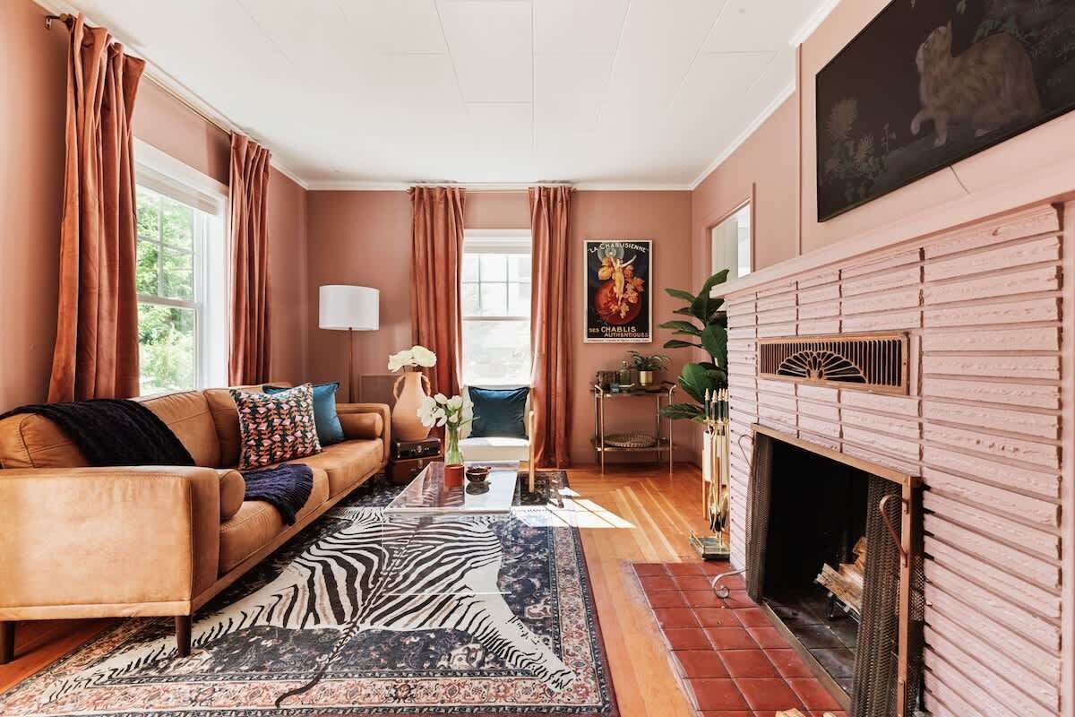 Una sala de estar con un sofá, un tapete estampado de cebra, una chimenea y una ventana con cortinas.
