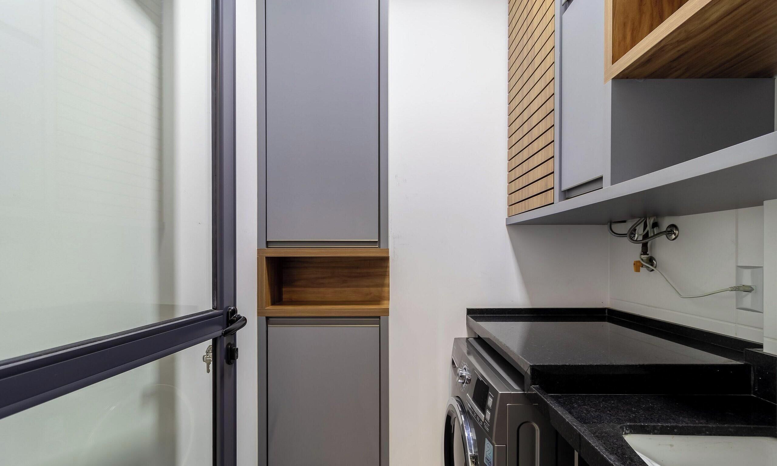 A compact kitchen with a built-in oven, a small wooden shelf, and a black countertop.