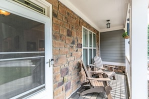 A porch with a stone wall, two Adirondack chairs, and a sliding glass door. - Family Escape | Movie/Game Lounge, Near Downtown (Mableton)