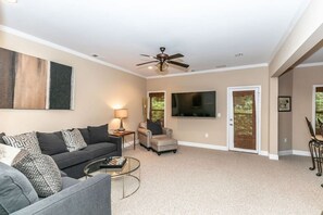 A living room with a sofa, armchair, coffee table, and a ceiling fan. - Family Escape | Movie/Game Lounge, Near Downtown (Mableton)
