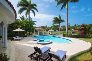 A swimming pool with lounge chairs and umbrellas, surrounded by palm trees and a well-maintained lawn. - Private 4BR Villa with Pool inside All-Inclusive Beach Resort, Puerto Plata (Puerto Plata)