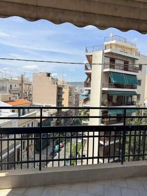 Ein Balkon mit Blick auf eine Stadtansicht, mit mehrstöckigen Gebäuden und blauem Himmel.