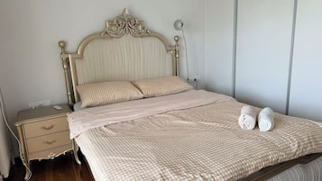 Ein Bett mit karierter Bettdecke, ein Nachttisch mit Schublade und eine Wandleuchte.