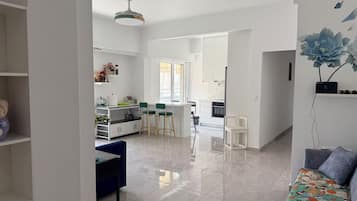 Ein moderner Wohnraum mit Essbereich, Küche und einer Couch mit Blumenmuster-Decke.