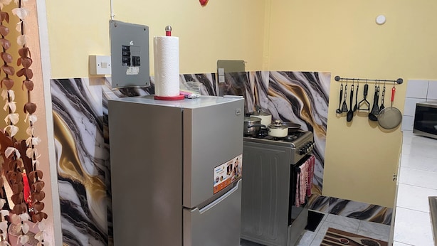Uma cozinha com geladeira, fogão e diversos utensílios.