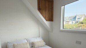 Ein Schlafzimmer mit einem Bett, Kissen, einem Fenster und einem Holzschrank.