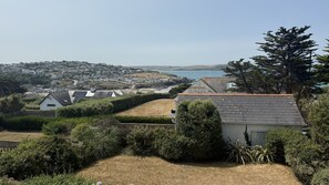 A residential area with houses, a clear sky, and a view of the sea. - BellaVista 1B-Sleeps 4 in 2 Bedrooms (New Polzeath)