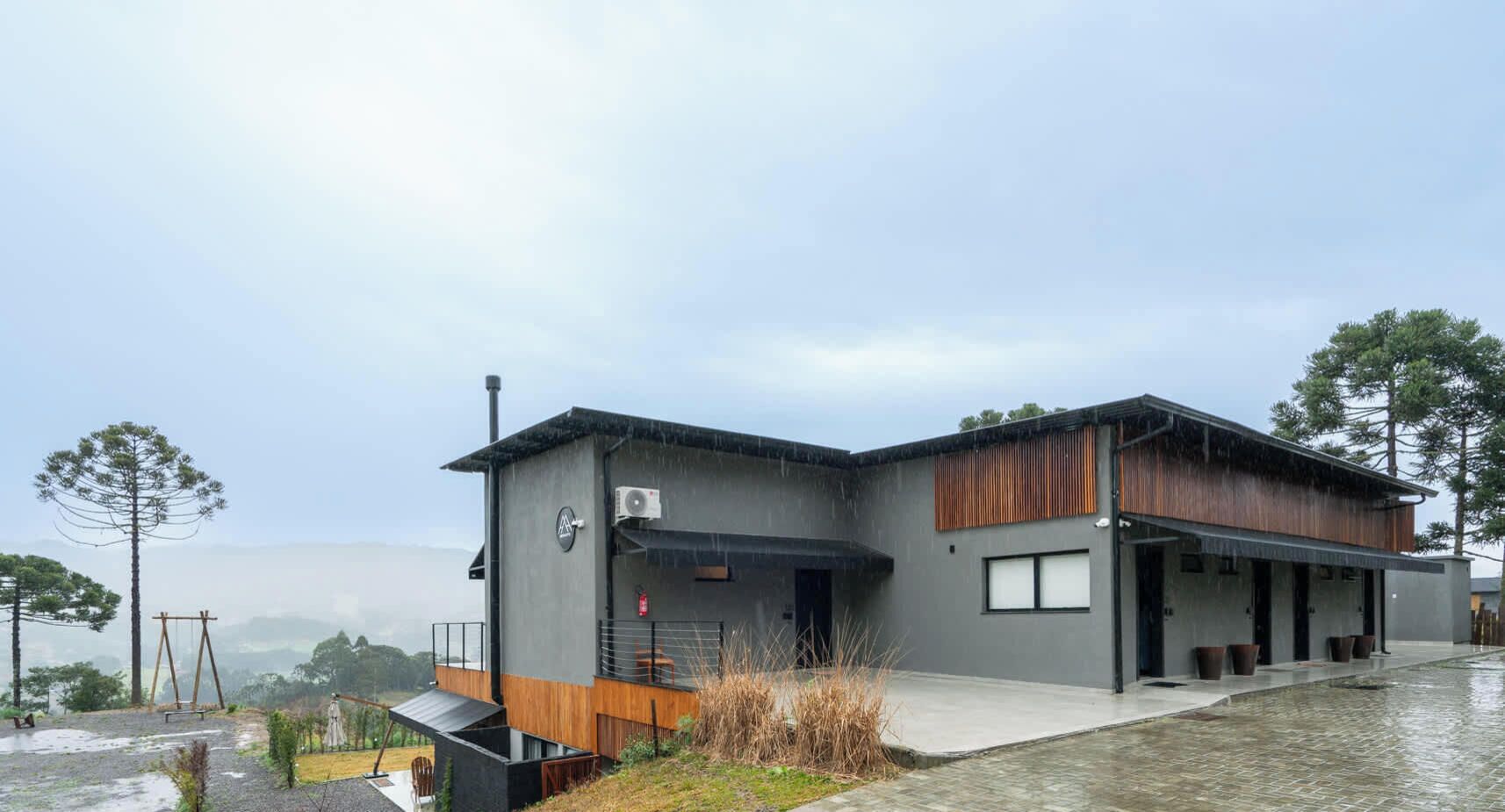 A modern building with a flat roof, a covered outdoor area, and a view of the surrounding landscape.