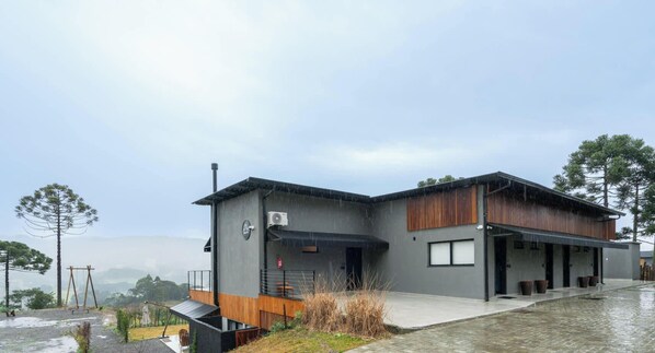 A modern building with a flat roof, a covered outdoor area, and a view of the surrounding landscape.