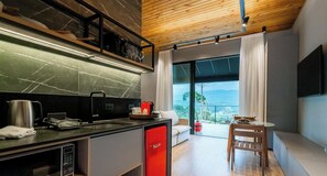 A modern kitchen with a built-in stove, a red refrigerator, and a dining area with a table and chairs.