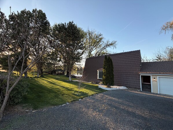A residential property with a gravel driveway, a garage, and a well-maintained lawn.