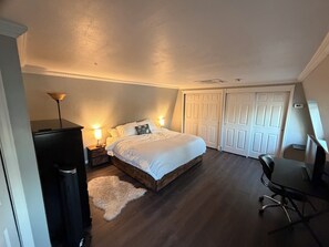 Ein Schlafzimmer mit einem Bett, Nachttischlampen, einem Schreibtisch und einem Stuhl.
