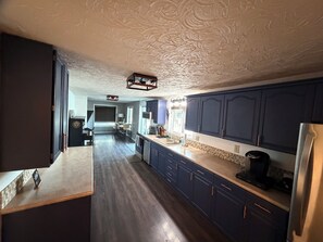 A kitchen with dark blue cabinets, a stainless steel refrigerator, and a wooden countertop.