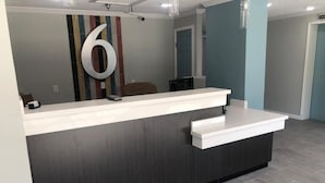 A reception desk with a dark wood finish, a large number '6' on the wall, and a striped rug on the floor. - Studio 6 – Vicksburg, Ms – Mississippi River (Vicksburg)