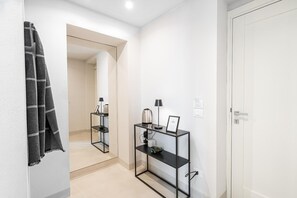 A hallway with a mirror, a black console table with a lamp, and a door. - Loggiato Verga 18th Cent   Suite Carrara Bed&Bros (SIRACUSA)