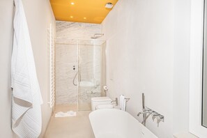 Ein modernes Badezimmer mit einer gläsernen Duschkabine, einer freistehenden Badewanne und einem WC.
