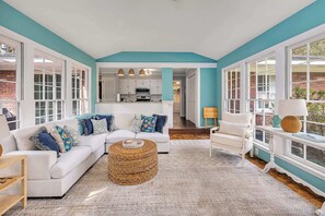 A spacious living room with a white sofa, a round woven coffee table, and a white armchair. - Tabby and Teal Cottage SSI (St. Simons Island)