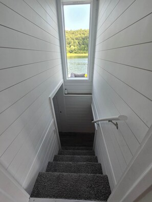 Eine Treppe mit Blick auf einen See und Wald durch ein Fenster.