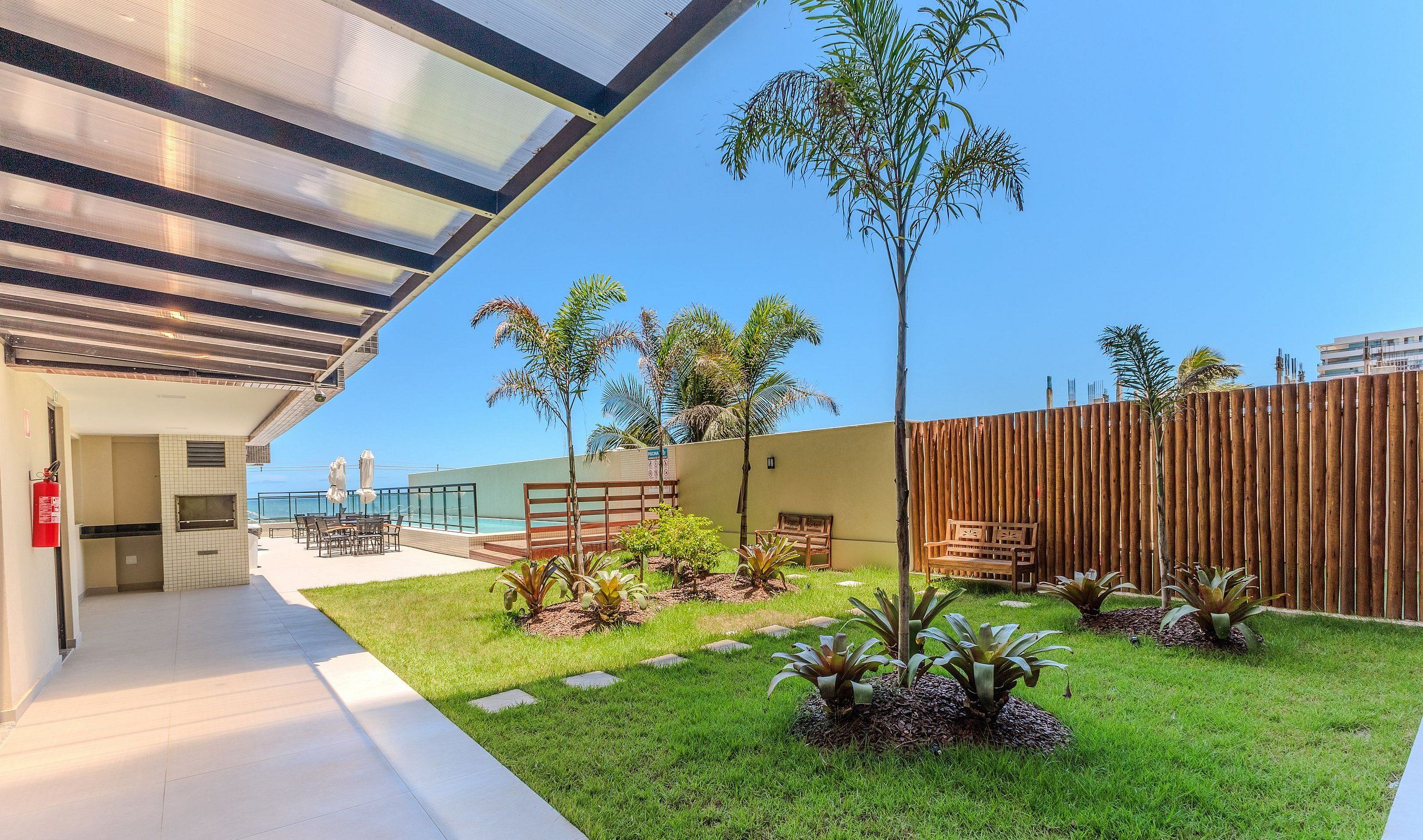 A modern outdoor area with a covered seating area, a pool, and a wooden fence.