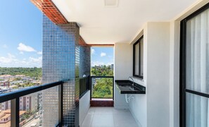 Un balcone con vista su una zona residenziale, un lavandino e una finestra con persiane.