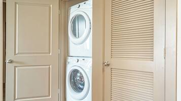 A laundry room with two stacked front-loading washing machines and a door with a vent.