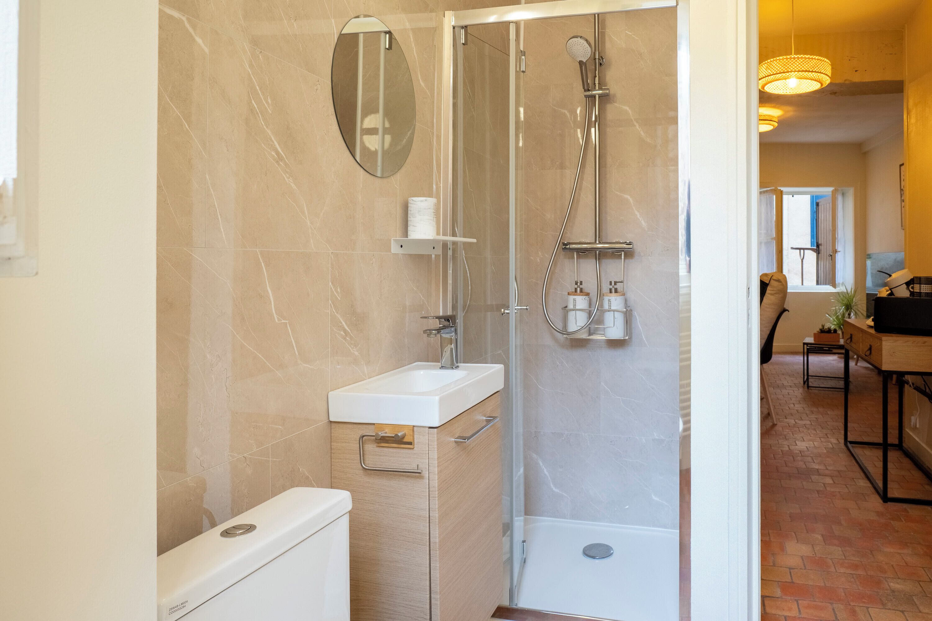 Une salle de bain moderne avec une douche à parois de verre, un lavabo blanc et des toilettes.