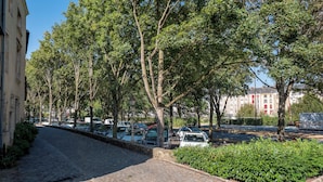 Eine von Bäumen gesäumte Kopfsteinpflasterstraße mit parkenden Autos.