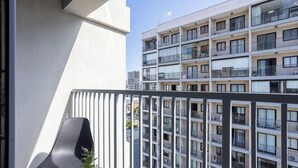 Um edifício moderno com várias varandas, uma planta visível e um céu limpo.
