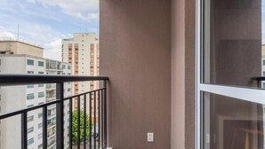 A balcony with a metal railing, a window, and a view of adjacent buildings. - Complete Studio 500m From the Subway Cpm1110 (São Paulo)