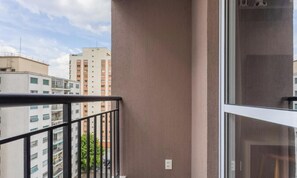 A balcony with a metal railing, a window, and a view of adjacent buildings. - Complete Studio 500m From the Subway Cpm1110 (São Paulo)