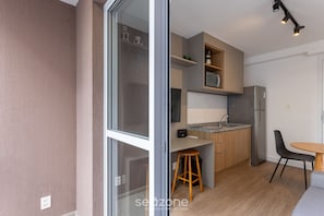 Eine moderne Küche mit Holzschränken, einem Edelstahlkühlschrank und einer kleinen Essecke mit Tisch und Stühlen.