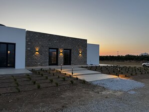 Un edificio moderno con fachada de piedra, ventanas amplias e iluminación exterior.