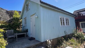 Una casa de madera azul claro con techo inclinado, un porche con banca y una estatua de piedra.