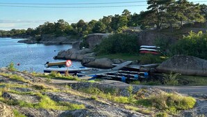 Una costa rocosa con barcos y un letrero de prohibido el acceso.