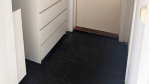 Una habitación con una puerta blanca, un estante pequeño con toallas dobladas y un cuchillo sobre el estante.