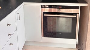 Una cocina con horno empotrado, estufa y microondas.