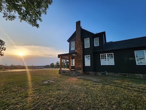 A two-story house with a brick chimney, a covered porch, and a view of the sunset. - Farm House at Newberry. (Newberry)