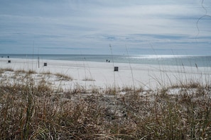 A beach with sand, sparse vegetation, and a clear sky. - Coastal Bliss and Beachfront Resort Oasis for 5! (Panama City Beach)