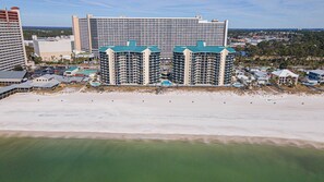 Un hotel frente a la playa con varios edificios altos, una playa de arena y una vista despejada del océano.