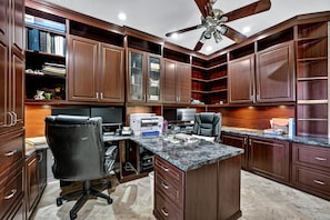 A spacious home office with a large desk, office chair, and a ceiling fan. - Stunning vacation rental in the prestigious Mirage Cove gated community. (Rancho Mirage)