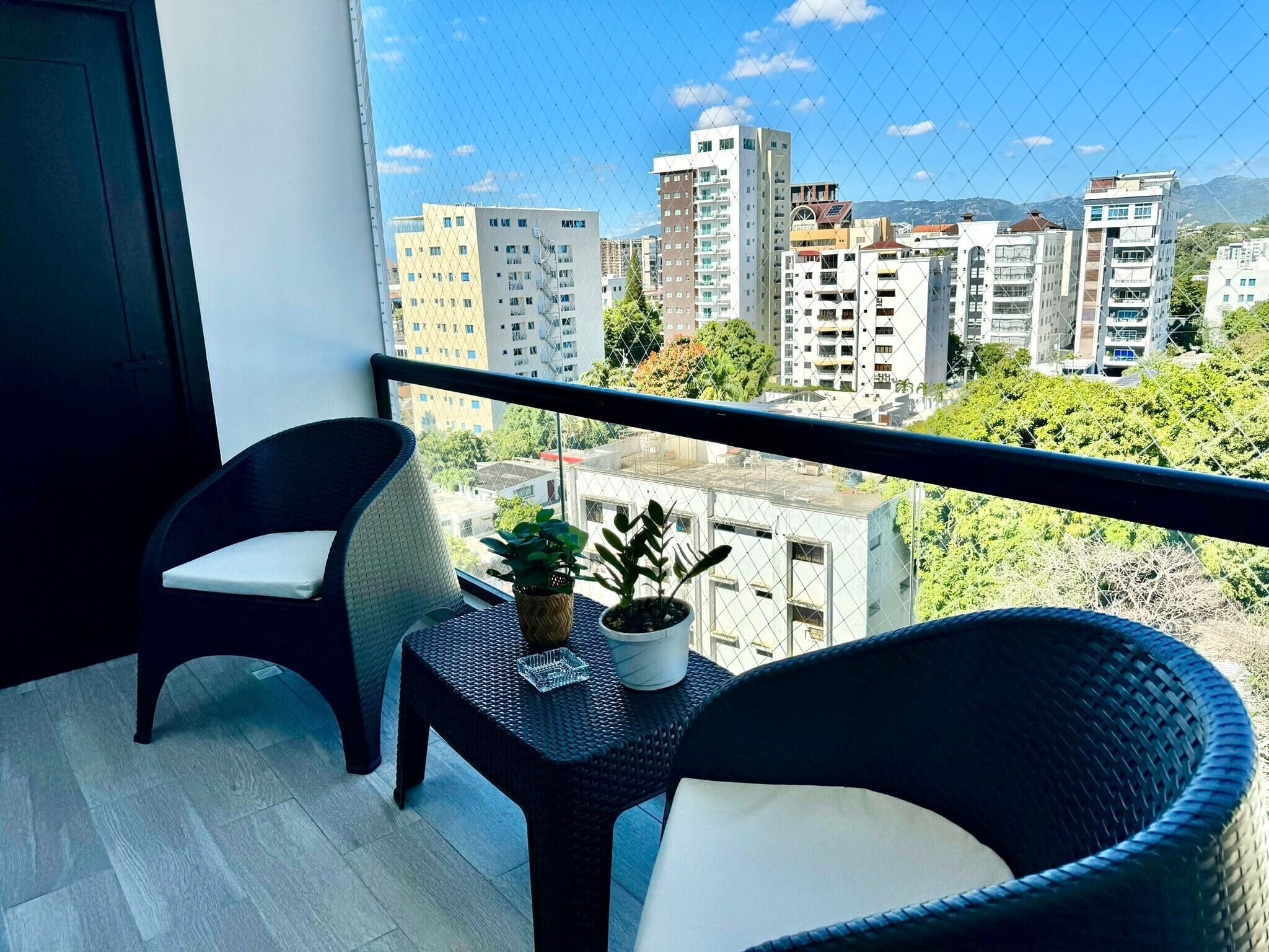 A balcony with two wicker chairs and a small table with potted plants.
