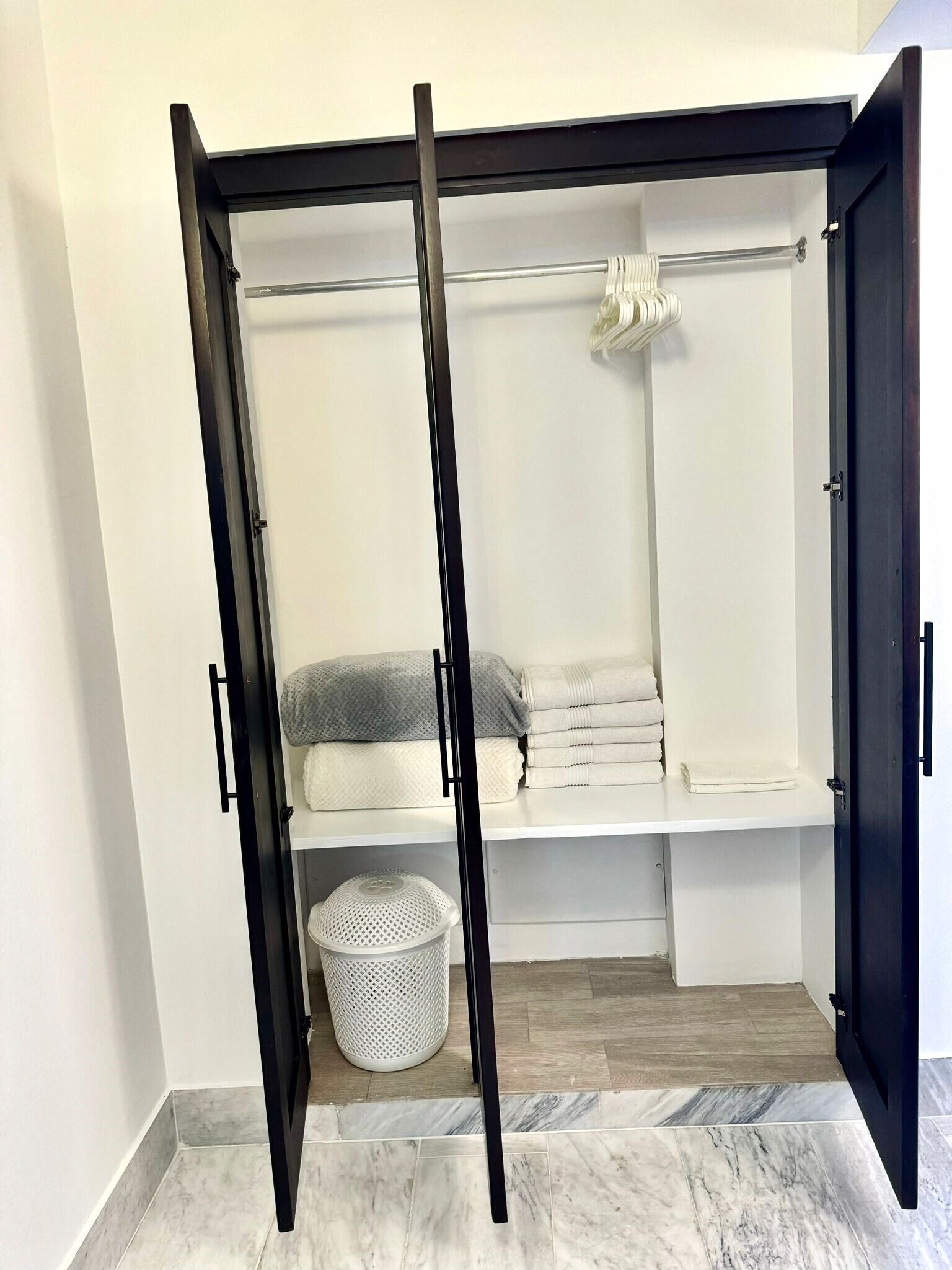 Et walk-in closet med skydedør, en bøjlestang, en hylde og en opbevaringskasse.