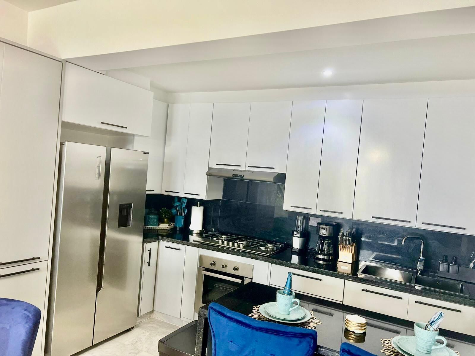 A modern kitchen with white cabinets, stainless steel appliances, and a black countertop.